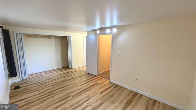 a view of an empty room with window and wooden floor