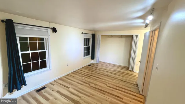 a view of empty room with wooden floor and windows