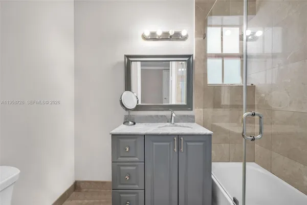 a bathroom with a granite countertop sink toilet and shower