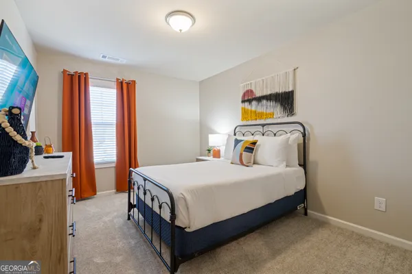 a bedroom with a bed and a flat tv screen on the dresser