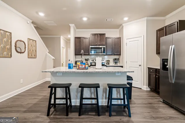 a kitchen with stainless steel appliances granite countertop a dining table chairs refrigerator and microwave