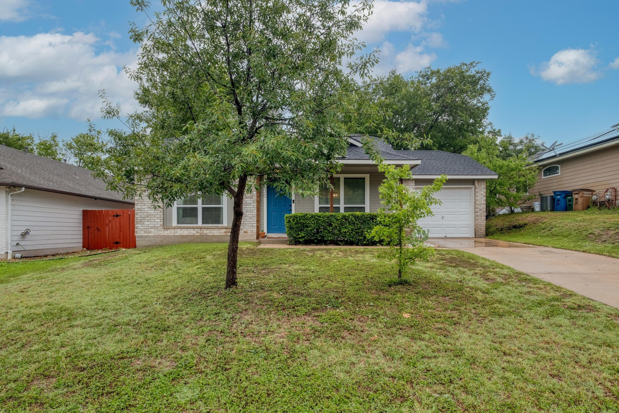 Inviting entryway features a bold blue front door, brick accents, and covered porch seating.