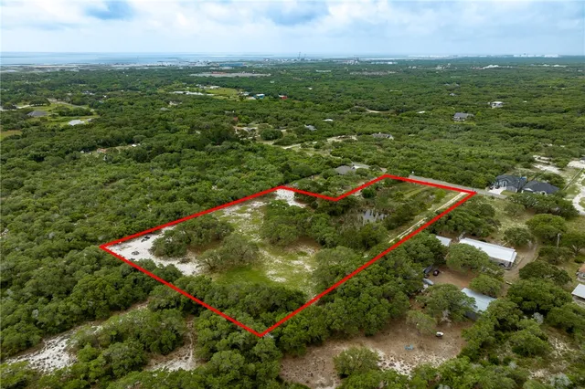 an aerial view of residential houses with outdoor space and trees