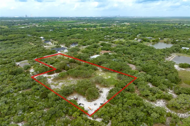 an aerial view of residential houses with outdoor space and trees