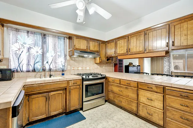 a kitchen with stainless steel appliances granite countertop a sink a stove and a refrigerator
