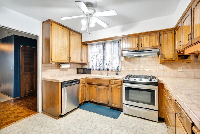 a kitchen with stainless steel appliances granite countertop a refrigerator a stove and a sink with cabinets