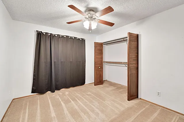 an empty room with a ceiling fan and carpet