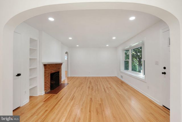 a view of empty room with wooden floor and fireplace