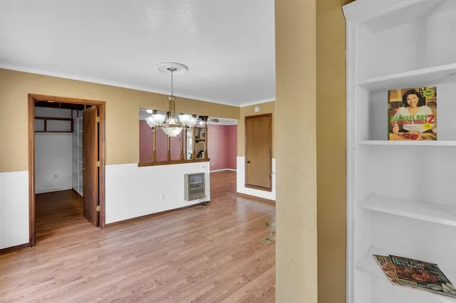 a view of a hallway with wooden floor and cabinet