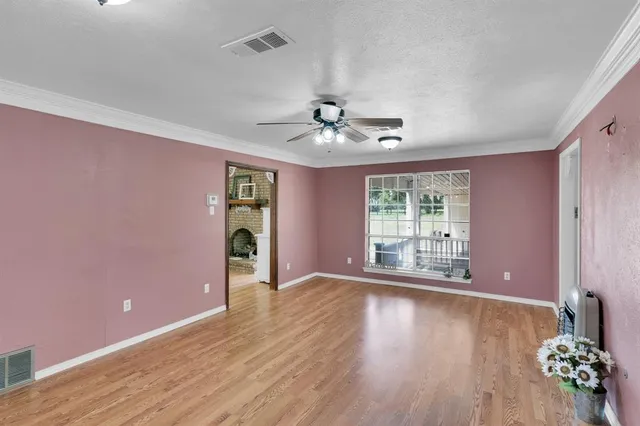 a view of an empty room with window and wooden floor