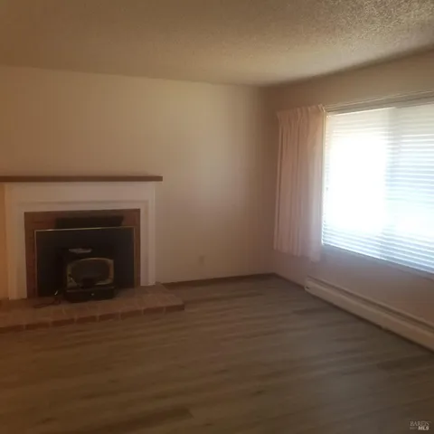 a view of empty room with wooden floor and a fireplace