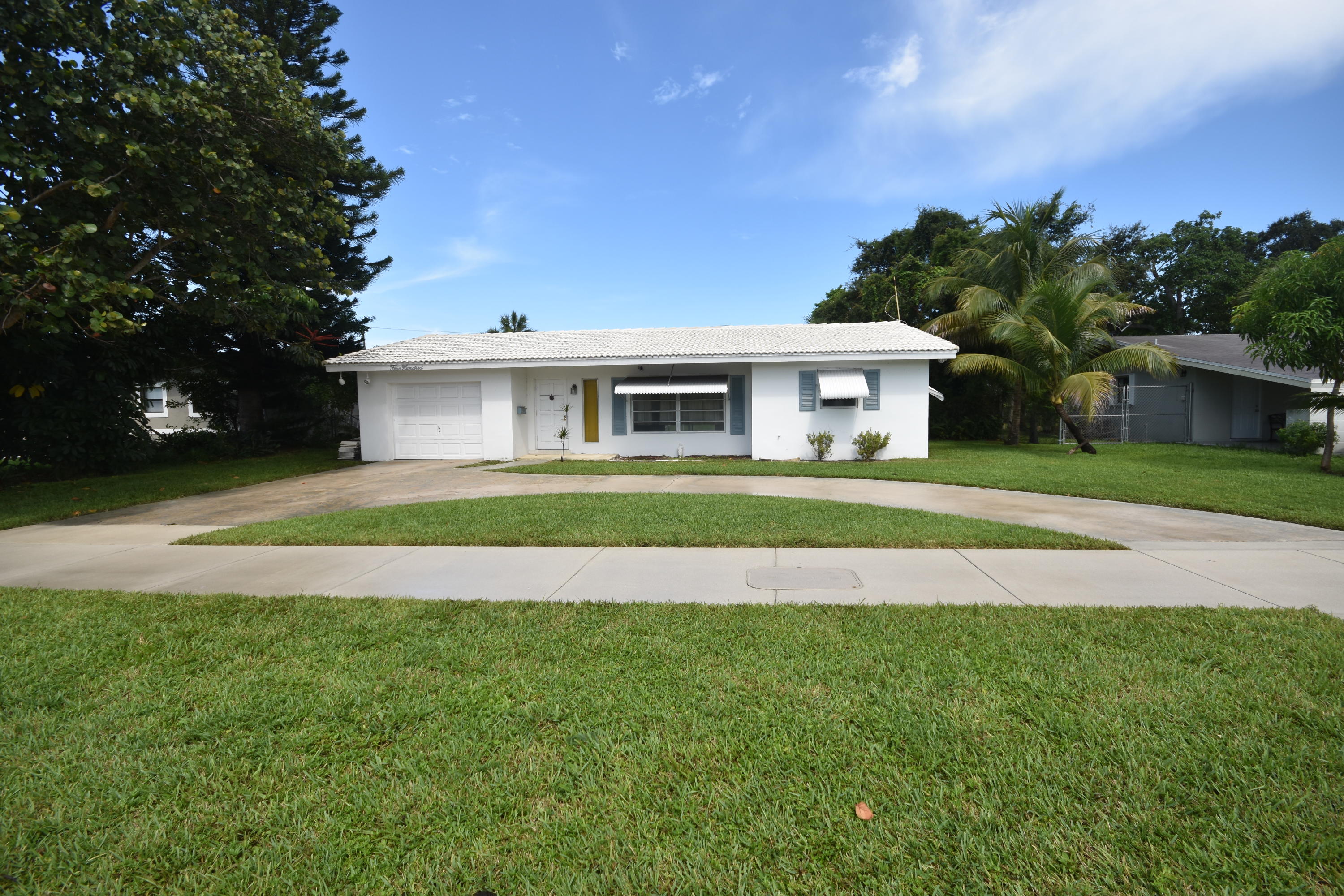 a front view of a house with a garden and trees