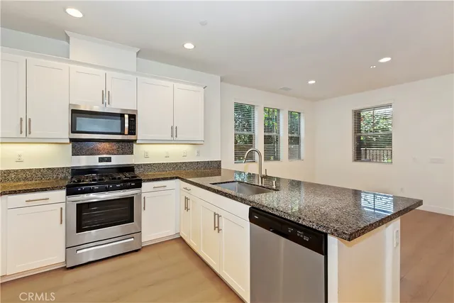 a kitchen with granite countertop stainless steel appliances a stove sink and microwave