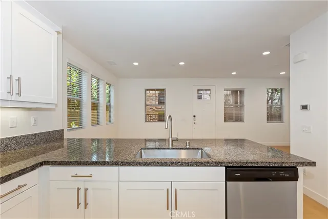 a kitchen with granite countertop white cabinets and a sink