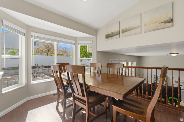 11189 Ohenry Road East Sandy, UT 84070 - Photo 12 of 44 Dining area featuring wood-finish flooring, a bay window with multiple panes, and a railing overlooking a lower level