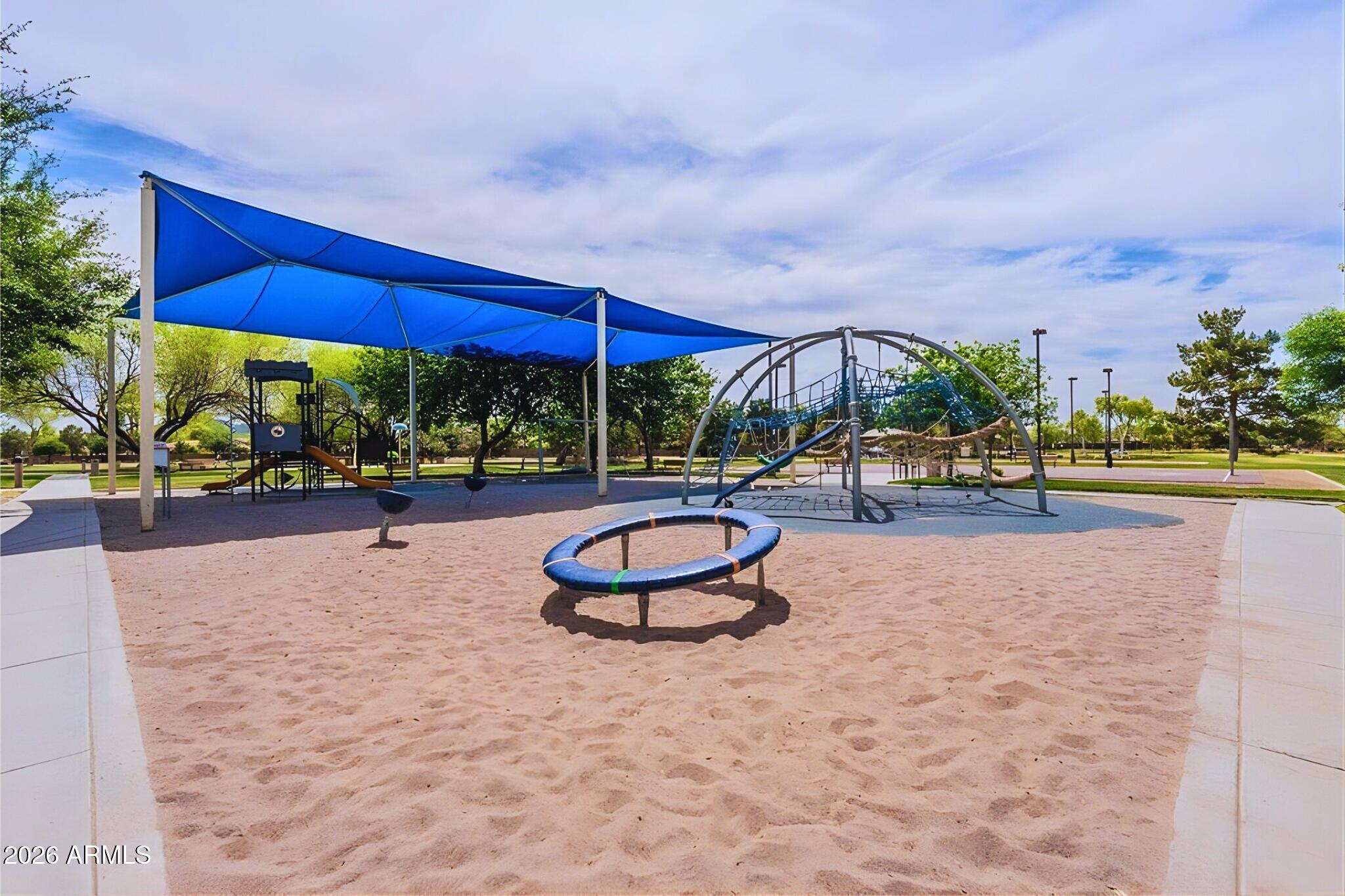 3936 East Blue Sage Road Gilbert, AZ 85297 - Photo 21 of 27 a view of a tennis ground with a table and chairs under an umbrella