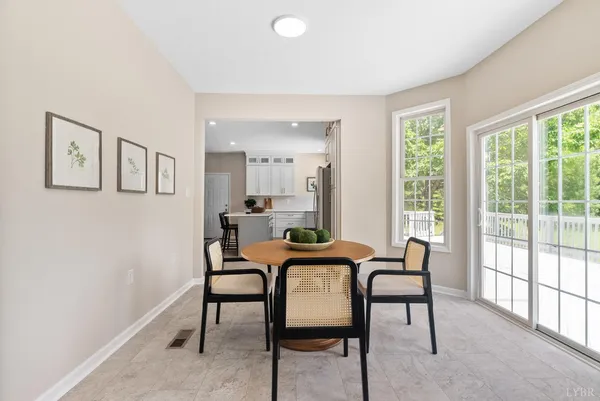 a kitchen with stainless steel appliances granite countertop a dining table chairs refrigerator and microwave