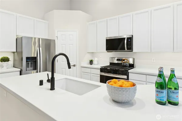 a kitchen with stainless steel appliances a stove a sink a refrigerator and cabinets