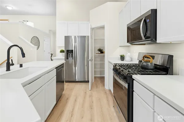 a kitchen with stainless steel appliances a stove microwave and sink