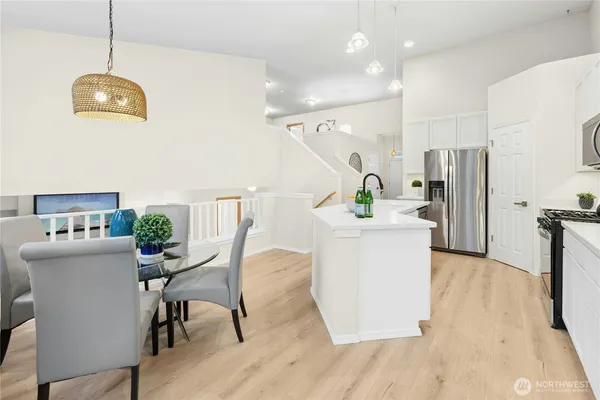 a kitchen with a dining table chairs refrigerator and microwave