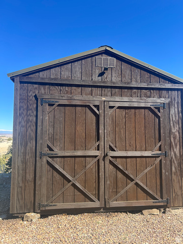 19075 West Honesty Cove Duchesne, UT 84021 - Photo 30 of 44 Gable-roofed shed with wood-finish siding, double barn doors featuring crossbuck detailing, and a louvered vent