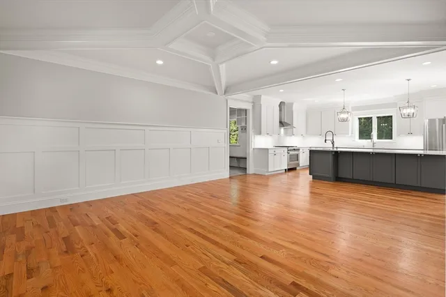 a view of empty room with wooden floor and kitchen view