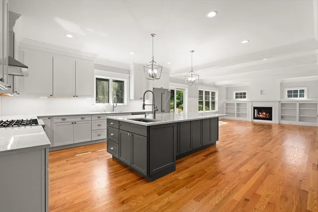 a kitchen with kitchen island granite countertop a stove top oven a sink a counter space and cabinets