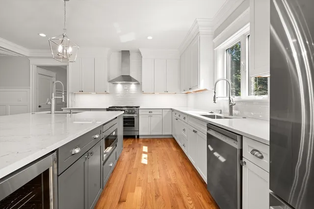 a large kitchen with a large counter top a sink stainless steel appliances and cabinets