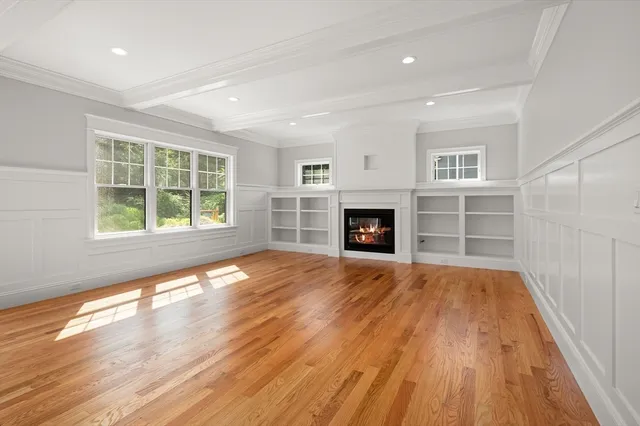 an empty room with wooden floor fireplace and windows