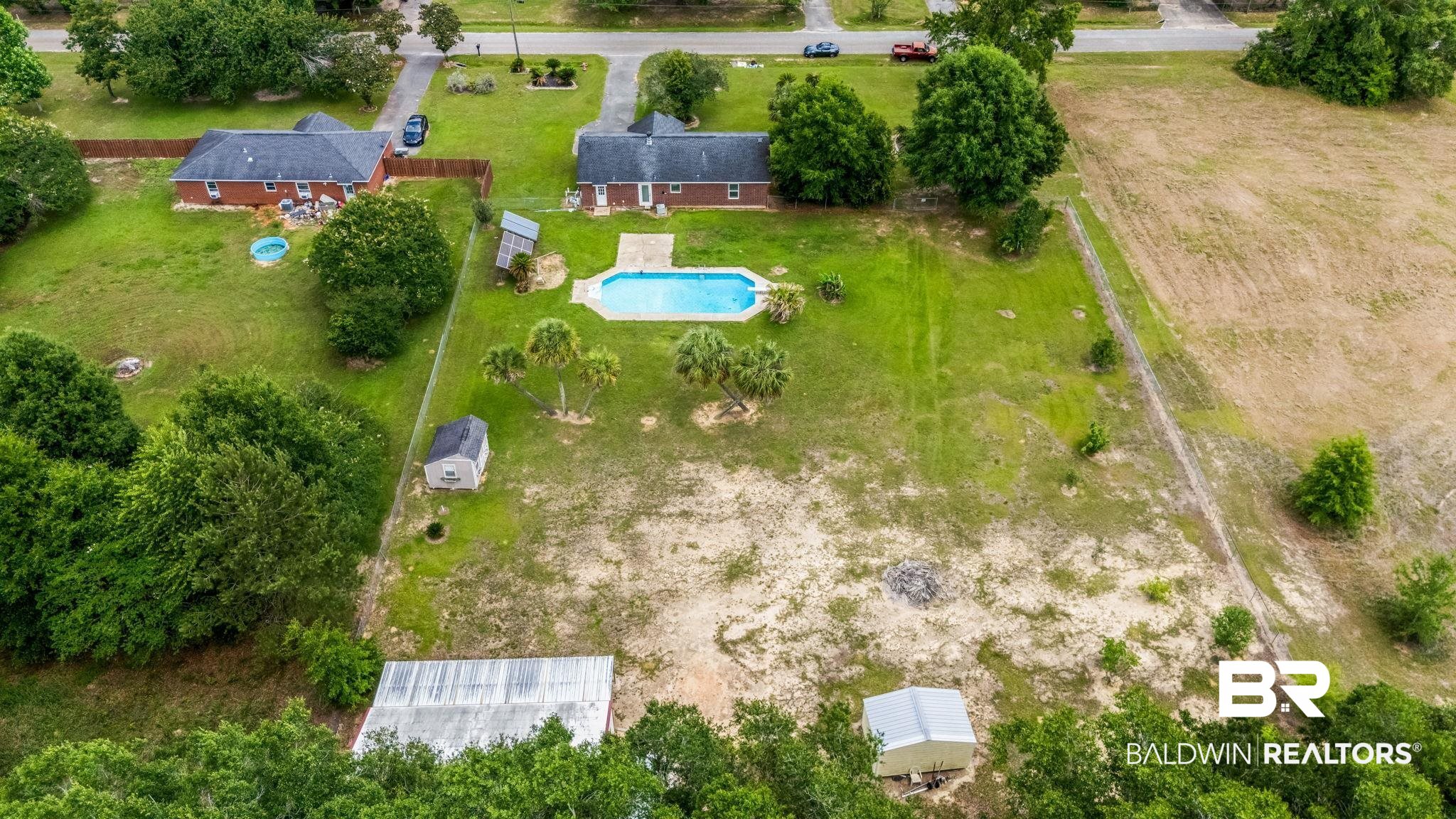 15096 Highland Circle Foley, AL 36535 - Photo 41 of 52 Expansive property featuring a inground swimming pool, several mature trees, and multiple outbuildings, including a large shed with a metal roof