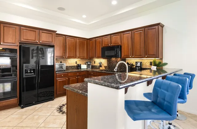 a kitchen with stainless steel appliances granite countertop a refrigerator a stove a sink and a microwave