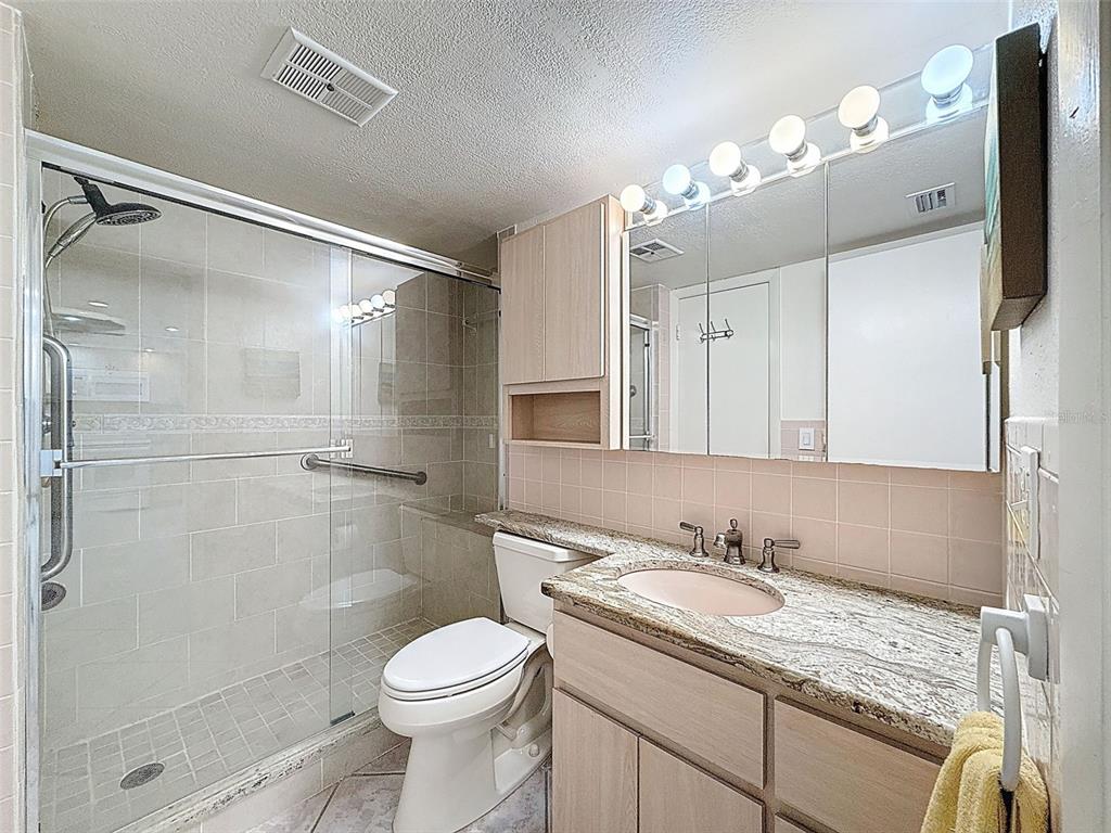 4550 Cove Circle, Unit 507 St. Petersburg, FL 33708 - Photo 17 of 32 a bathroom with a granite countertop sink toilet and shower
