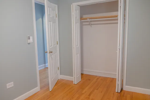 an empty room with wooden floor cabinet and windows