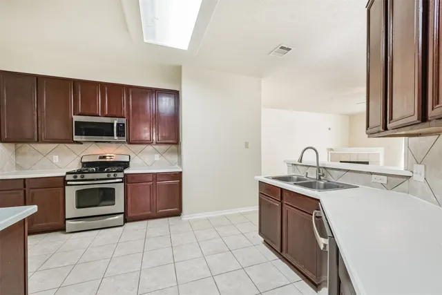 a kitchen with stainless steel appliances granite countertop a sink stove top oven and microwave