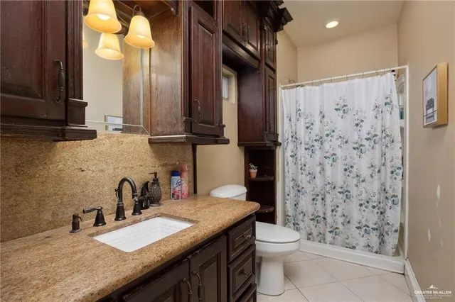 a bathroom with a granite countertop sink a toilet and a shower
