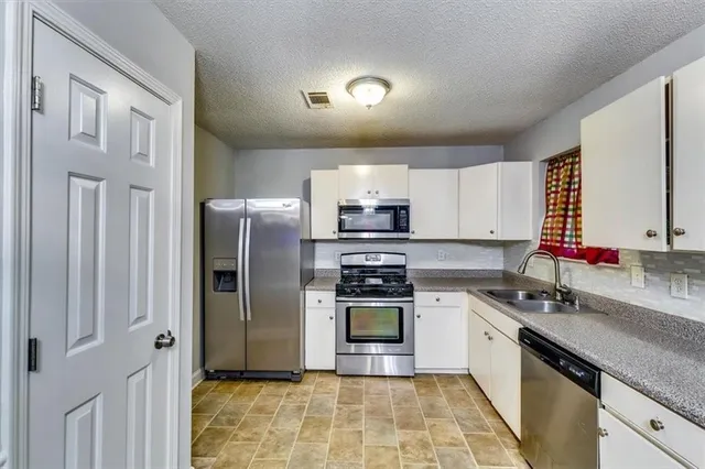 a kitchen with stainless steel appliances granite countertop a sink stove and microwave