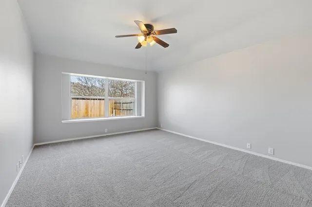 an empty room with ceiling fan and windows