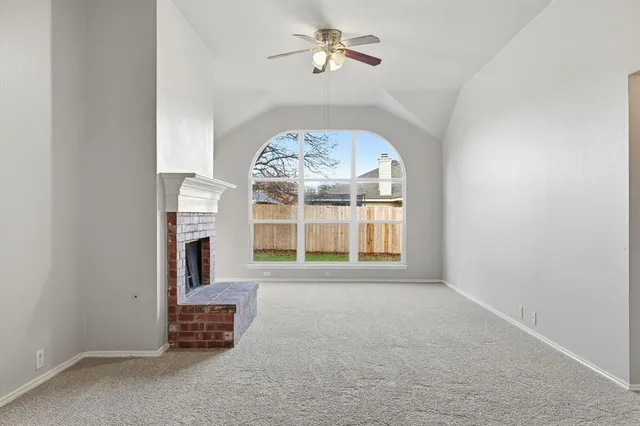 an empty room with windows and fireplace