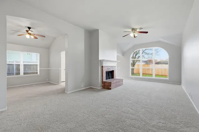 an empty room with a fireplace and windows