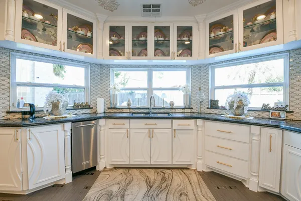 a kitchen with granite countertop white cabinets and a window