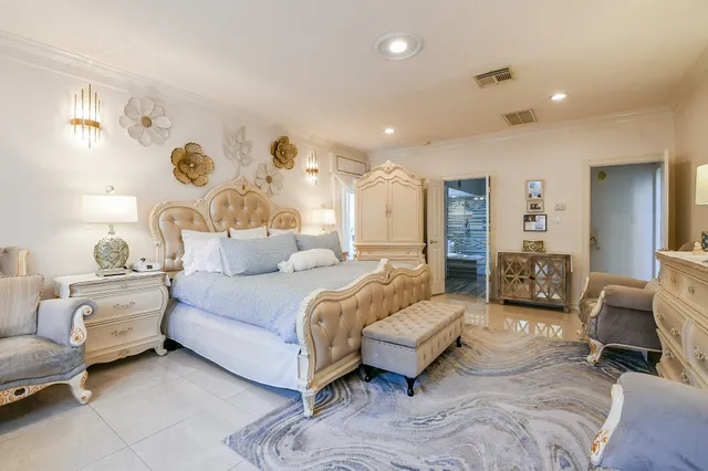a spacious bedroom with a bed a couch and a chandelier