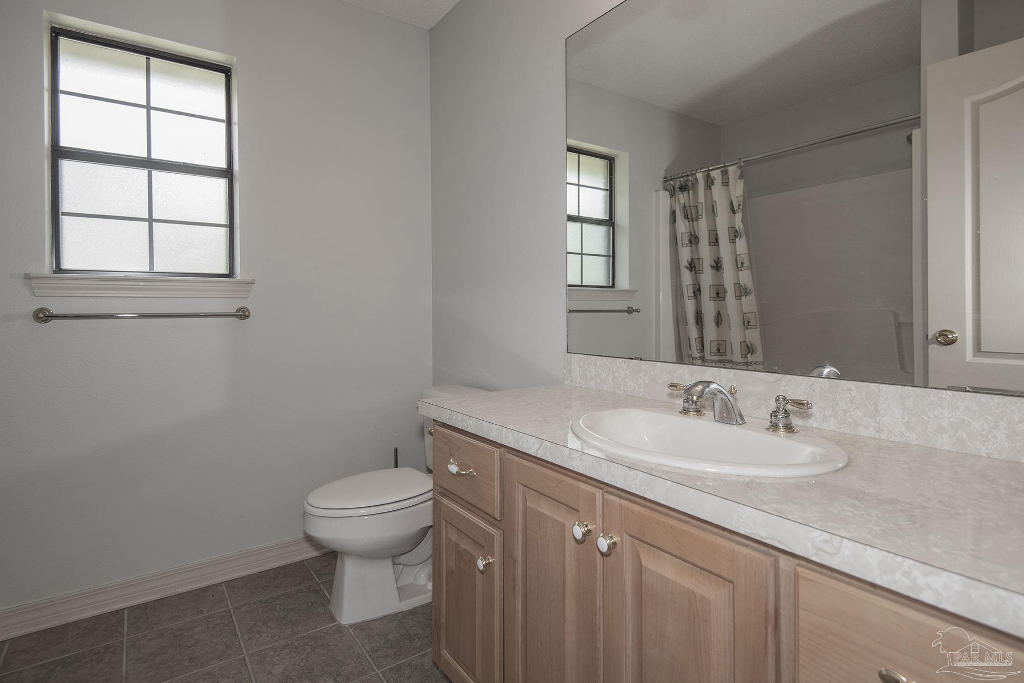 4565 South Spencer Field Road Pace, FL 32571 - Photo 13 of 49 a bathroom with a granite countertop sink a toilet and a window