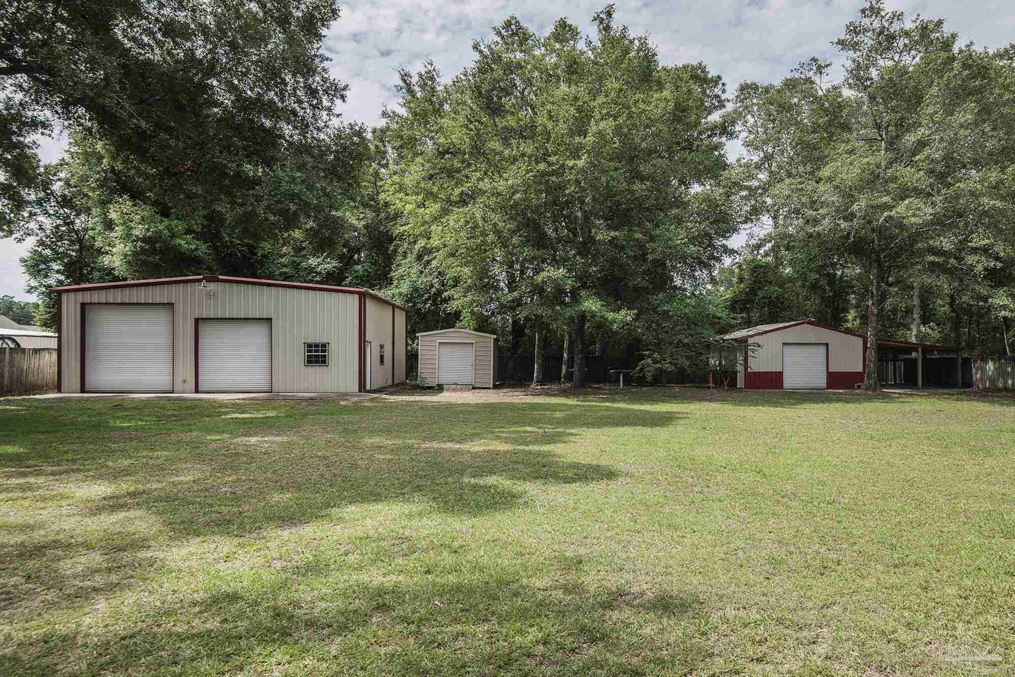 4565 South Spencer Field Road Pace, FL 32571 - Photo 36 of 49 a front view of a house with a garden and trees