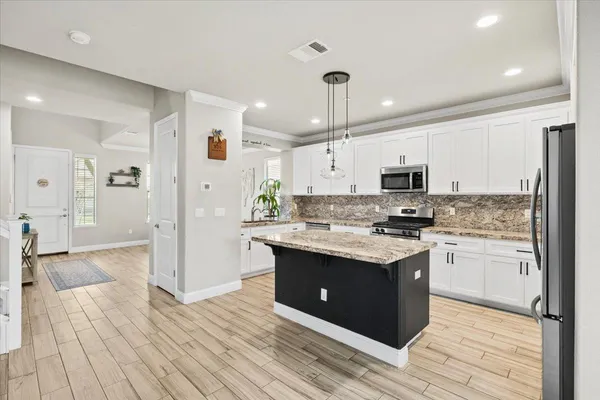 a kitchen with stainless steel appliances granite countertop a refrigerator a stove a sink and a microwave