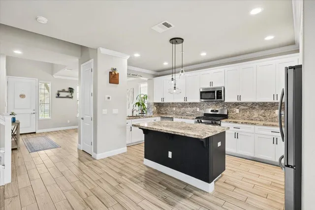 a kitchen with stainless steel appliances granite countertop a refrigerator a stove a sink and a microwave