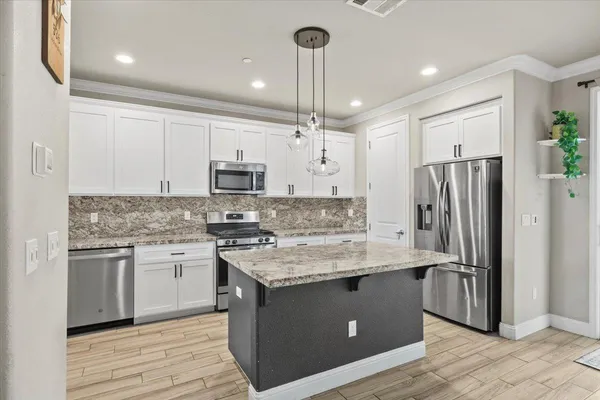 a kitchen with granite countertop a stove top oven microwave and cabinets
