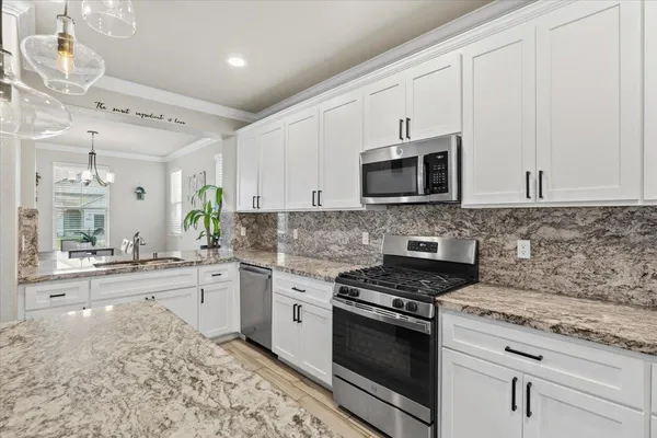 a kitchen with stainless steel appliances granite countertop a sink a stove and a wooden floors