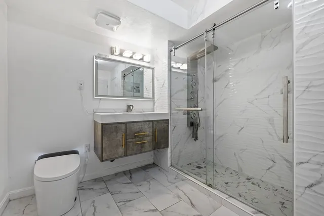 a bathroom with a granite countertop sink mirror and toilet