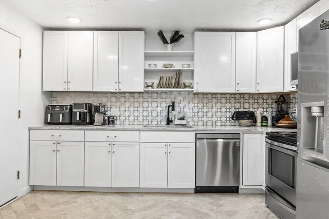 a kitchen with stainless steel appliances granite countertop a stove a sink and white cabinets