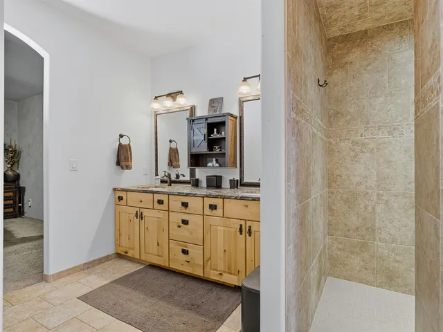 a bathroom with a granite countertop sink a mirror and shower